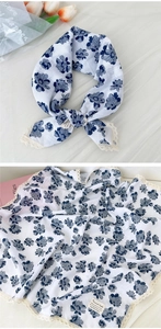 Dettaglio macro di sciarpa in cotone e lino con fiori blu e bordi in pizzo beige