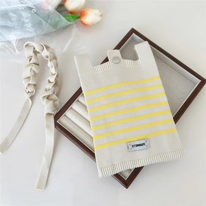 Detail of striped knitted tote bag with metallic snap closure and textured handle
