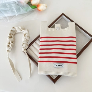 Detail of striped knit phone bag with STANNUM label and woven shoulder strap