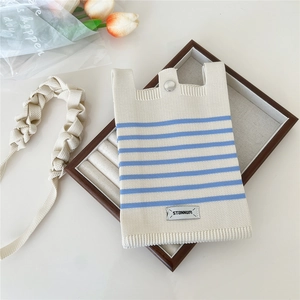 Close-up of a knitted striped mini crossbody bag with a metal button and woven strap