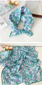 Detail of colorful floral silk scarf featuring elegant green stitched edges and soft fabric