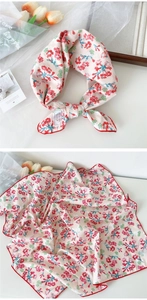 Detail of pink floral cotton scarf featuring red flower patterns and hand-rolled edges