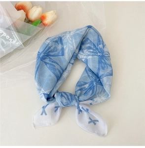 Détail du foulard en coton et lin bleu clair avec motifs de nœuds et coutures de bord fines