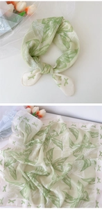 Détail d'un foulard en lin et coton vert clair avec motifs de feuilles et nœuds