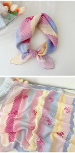 Détail de motifs ondulés roses et bleus avec nœuds rouges sur un foulard en coton et lin