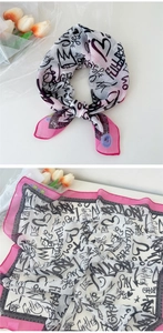Détail de l'écharpe à imprimé graffiti avec bord rose et motif de texte élégant