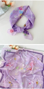 Détail d'un foulard en lin de coton lavande avec motifs colorés et bordure en dentelle