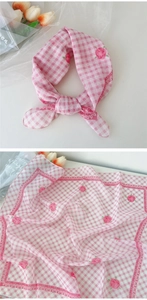 Détail d'un foulard carré en lin et coton à carreaux roses avec motifs de roses