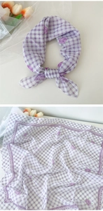 Détail d'un foulard en coton et lin à carreaux violets avec imprimé floral et bord ondulé