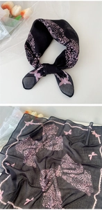 Détail d'un foulard en coton doux avec motif léopard noir, nœuds roses et zébrures fines
