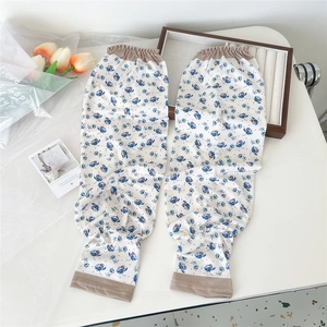 Floral print oversleeves with elastic cuffs on a clean white desk with tulips