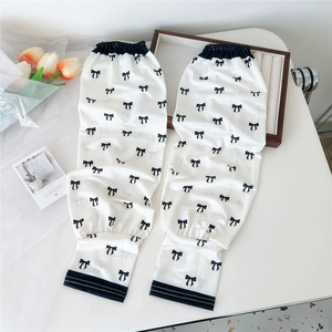 Detail of white cooling arm sleeves with sweet black bow patterns and elastic cuffs