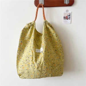 Close-up of yellow floral tote bag featuring drawstring closure and FANIA label