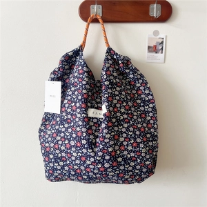 Detailed shot of floral canvas tote bag with woven rope handles and a side brand tag