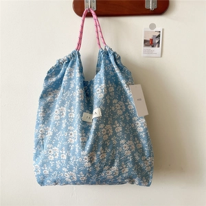 Detailed view of floral canvas tote with pink drawstring rope handles and woven label