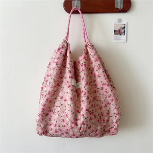 Detailed view of pink floral tote bag fabric texture with braided rope shoulder strap