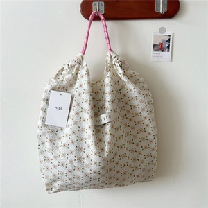 Close-up of floral tote bag featuring drawstring closure and pink braided rope handles