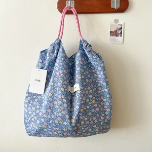 Detailed view of floral canvas tote with pink drawstring handles and a woven logo patch