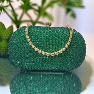 Detailed view of emerald green rhinestone evening clutch with gold clasp and chain