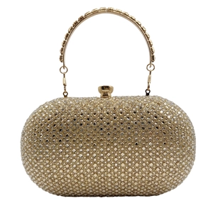 Close-up of golden clutch bag with shimmering rhinestones and a metal ring handle