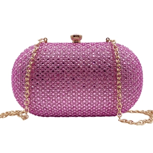 Detail of pink rhinestone clutch with golden gemstone clasp and metallic chain strap