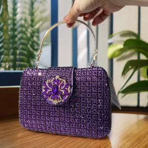 Detail of purple crystal clutch bag with jeweled floral clasp and gold handle