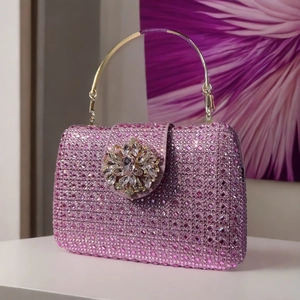 Close-up of pink crystal clutch bag with floral rhinestone buckle and gold handle