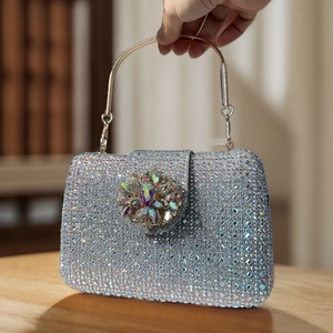 Macro view of silver rhinestone evening bag featuring a crystal floral embellishment