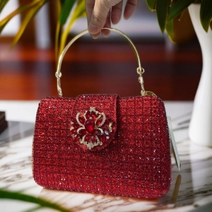 Close-up of red rhinestone evening bag with gold handle and flower gemstone buckle