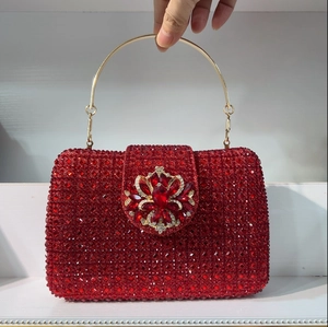 Detail of red crystal clutch bag with gold round handle and floral rhinestone clasp