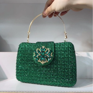 Detailed macro of a green rhinestone evening bag with floral emerald buckle and gold handle