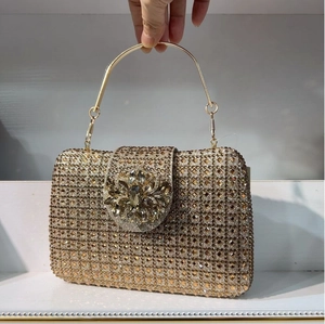 Detail of champagne gold crystal clutch with flower buckle and metallic top handle