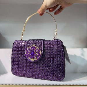 Detail of purple crystal clutch bag featuring flower rhinestone buckle and gold handle