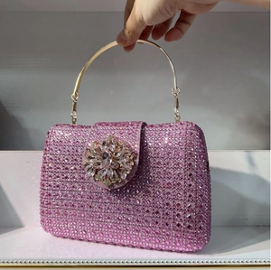 Detail view of pink rhinestone evening clutch featuring crystal floral buckle and gold handle