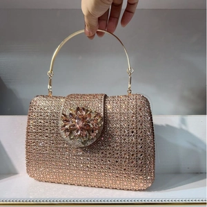 Macro detail of champagne gold crystal clutch with flower gemstone buckle and metal ring handle