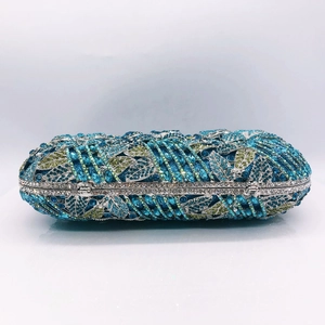 Detail of blue and green crystals on a hollow metal clutch bag with floral patterns