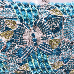 Macro detail of hollow metal clutch with blue and green rhinestones in butterfly pattern