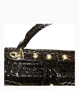 Vue détaillée d'un sac à main noir motif crocodile avec des finitions métalliques dorées