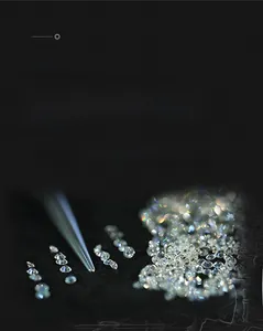 Macro view of round brilliant cut loose moissanite gems with tweezers on black background