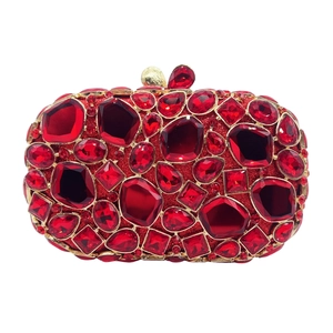 Detailed view of red rhinestones and crystals on a hollow-out gold luxury clutch bag