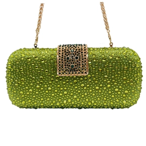 Macro shot of green rhinestone evening clutch with fine golden metal chain and hardware