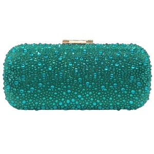 Detailed close-up of luxurious emerald green rhinestones and golden metal clasp