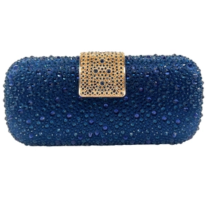 Close-up of a dark blue rhinestone clutch bag with a golden filigree metal clasp