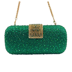 Detail of green rhinestone clutch bag featuring golden metal frame and chain strap