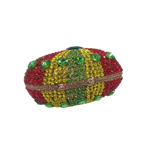 Detail of oval evening clutch bag with colorful rhinestones and green heart gemstone