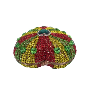 Macro detail of heart-shaped evening bag featuring tricolor rhinestones and green gemstone