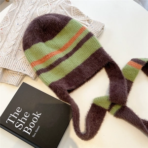 Vue à plat d'un bonnet en tricot rayé avec de longs glands sur fond blanc doux