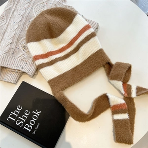 Détail du bonnet en maille mohair à rayures avec cache-oreilles sur table crème