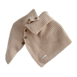 Two-tone knit turtleneck collar with amber buttons on soft beige ribbed wool material
