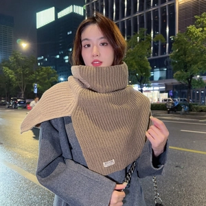 Detail of khaki chunky knit high collar neck warmer with brand logo tag and woven texture